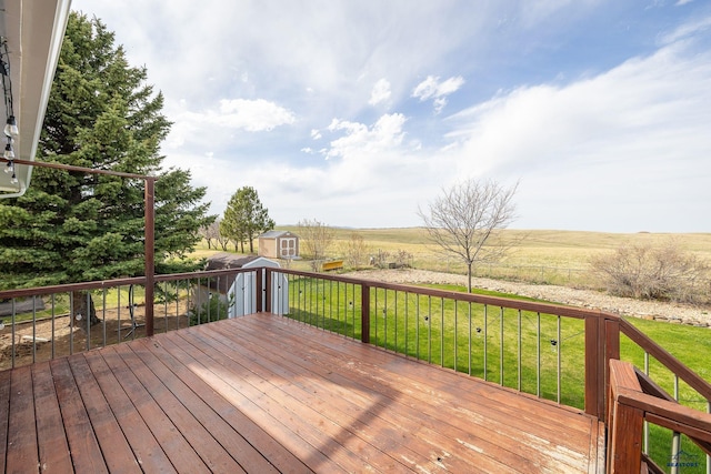 deck with a lawn, a rural view, a storage unit, and an outdoor structure