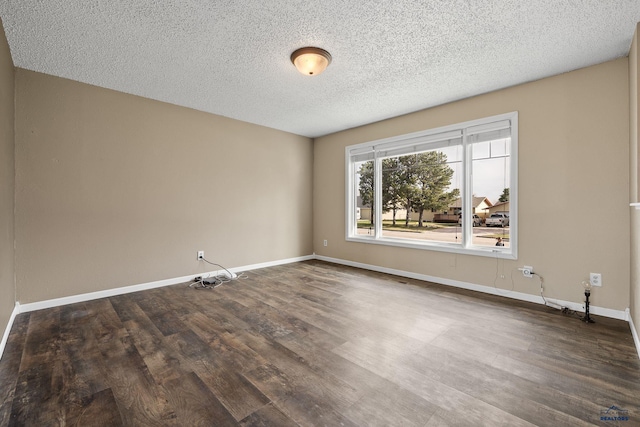 spare room with baseboards, a textured ceiling, and dark wood-type flooring