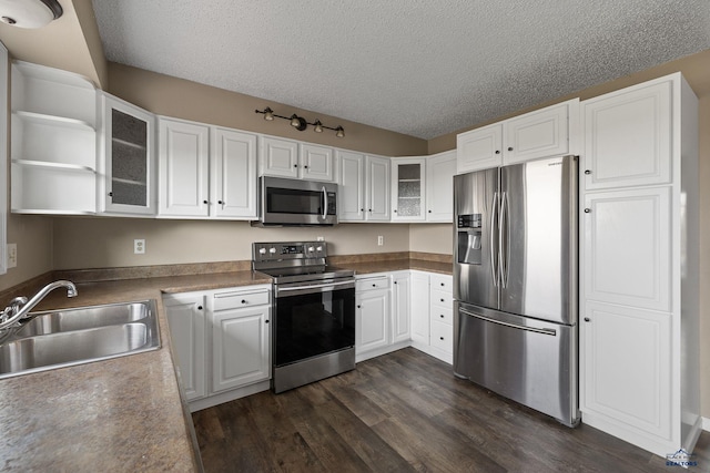kitchen with a textured ceiling, a sink, dark wood finished floors, white cabinetry, and appliances with stainless steel finishes