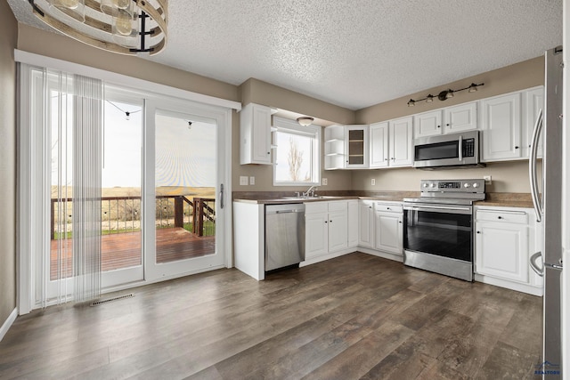 kitchen featuring white cabinets, stainless steel appliances, dark wood-style floors, and a textured ceiling