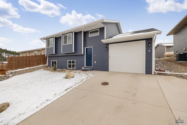 1073 Quinn Dr, Hill City, SD 57745 - view of front facade featuring central air condition unit, an attached garage, fence, and concrete driveway