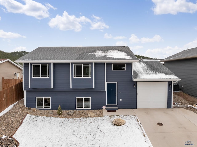 1073 Quinn Dr, Hill City, SD 57745 - bi-level home featuring fence, a shingled roof, entry steps, concrete driveway, and an attached garage