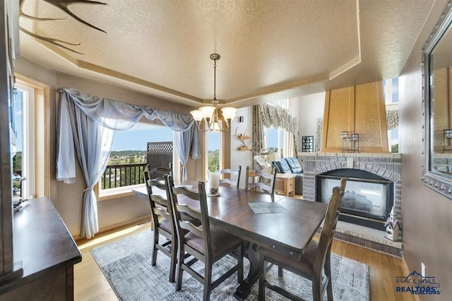 5325 Snowberry Ct, Rapid City, SD 57702 - dining area with a chandelier, a raised ceiling, light wood-style flooring, and a textured ceiling