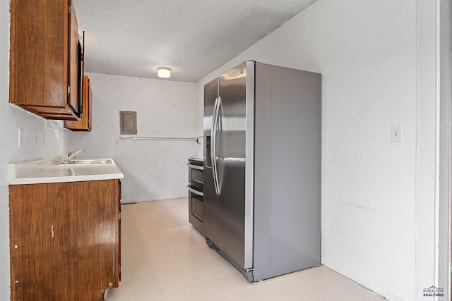 235 E E St, Patrick, Rapid City, SD 57701 - kitchen with a sink, appliances with stainless steel finishes, brown cabinetry, and light countertops