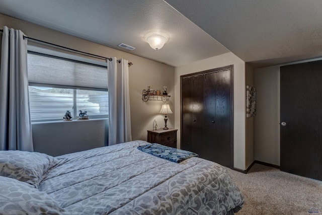 bedroom featuring a textured ceiling, visible vents, carpet floors, and baseboards
