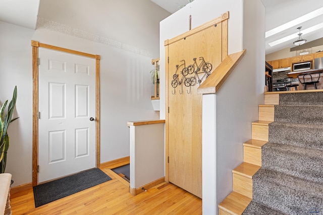 stairway featuring baseboards, wood finished floors, and vaulted ceiling