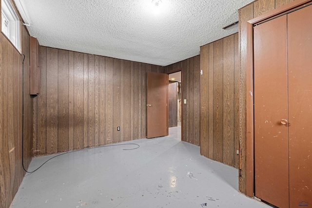 1937 Hillsview Dr, Rapid City, SD 57702 - unfurnished bedroom featuring visible vents, wooden walls, a textured ceiling, and unfinished concrete flooring