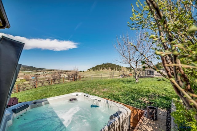 view of yard featuring a rural view, a fenced backyard, and a hot tub