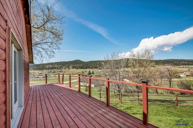 wooden deck with a rural view, a yard, and a mountain view