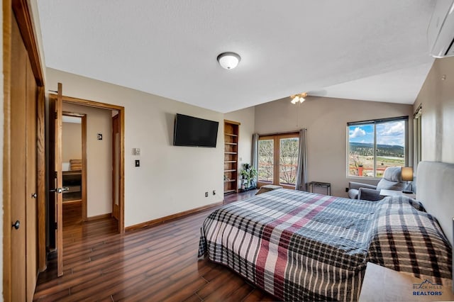 bedroom featuring a wall unit AC, vaulted ceiling, wood finished floors, and baseboards