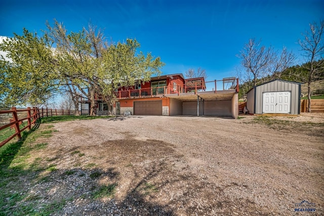 view of front of property with driveway, a storage shed, fence, and an outdoor structure