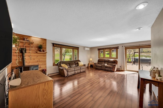 living room featuring a textured ceiling, a healthy amount of sunlight, wood finished floors, and a wall mounted AC