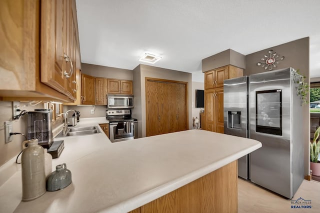 kitchen featuring appliances with stainless steel finishes, light countertops, a sink, visible vents, and a peninsula