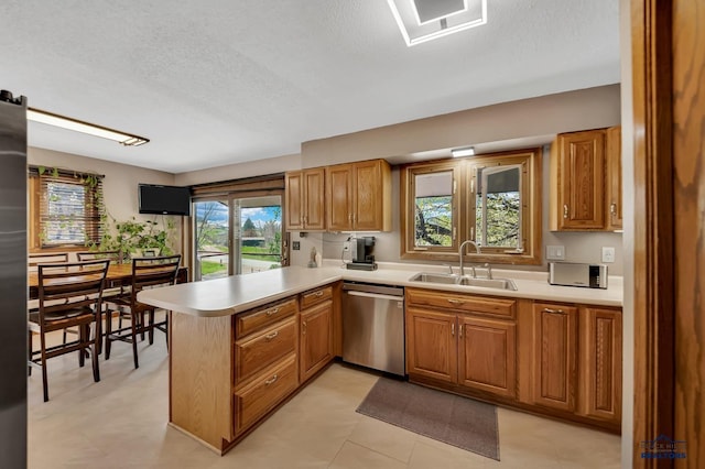 kitchen featuring stainless steel appliances, light countertops, a peninsula, and a sink
