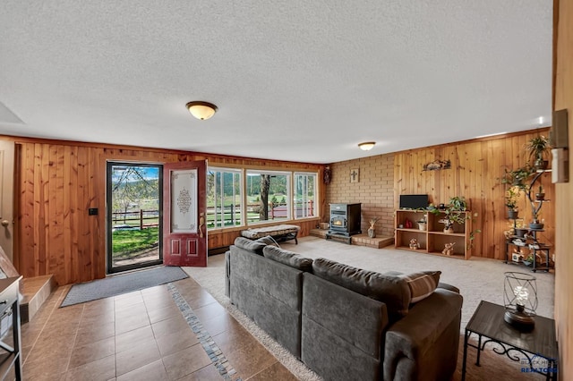 living room featuring wooden walls, a wood stove, and plenty of natural light