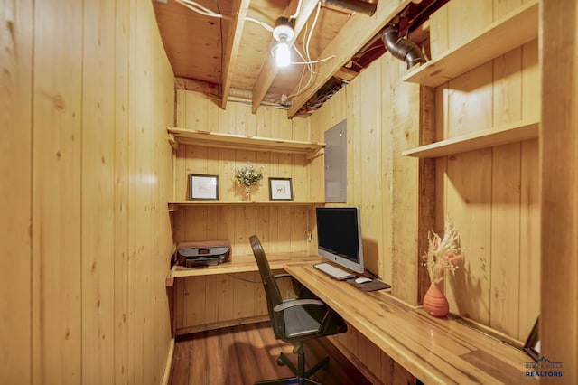 office space with wooden walls, built in desk, and wood finished floors