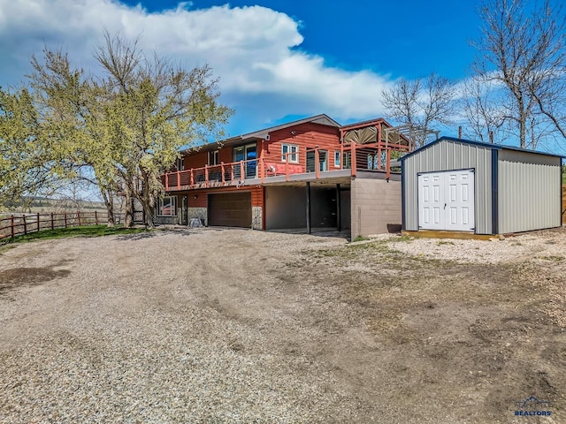 exterior space with driveway, an outdoor structure, a wooden deck, an attached garage, and fence
