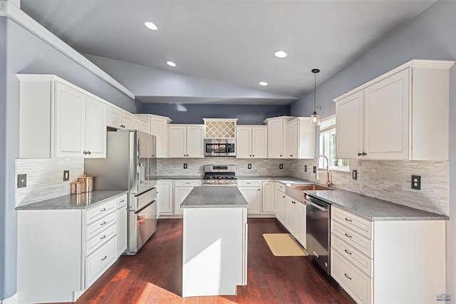 kitchen with tasteful backsplash, a center island, vaulted ceiling, white cabinets, and appliances with stainless steel finishes