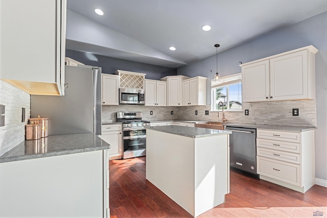 kitchen featuring lofted ceiling, a sink, backsplash, and stainless steel appliances