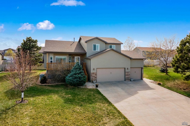 tri-level home with a front yard, driveway, an attached garage, and fence