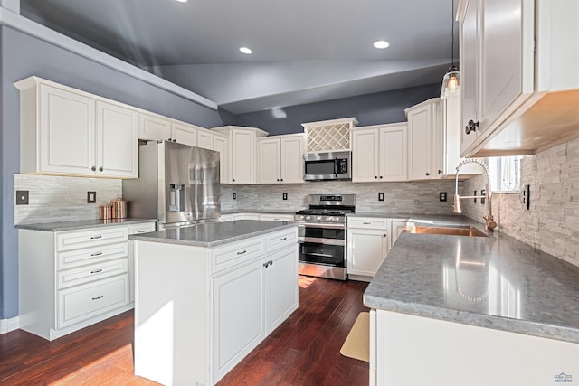 kitchen with appliances with stainless steel finishes, a kitchen island, dark wood-style flooring, a sink, and lofted ceiling