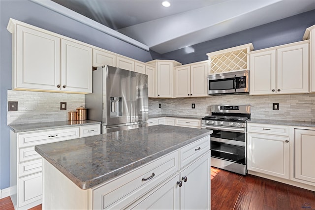 kitchen with dark wood-style floors, stainless steel appliances, a kitchen island, and dark stone counters