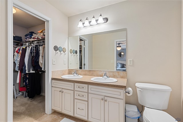 full bath with a spacious closet, toilet, double vanity, and a sink