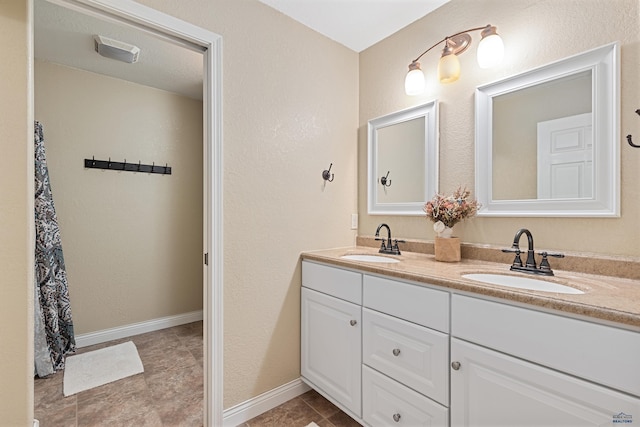 full bathroom featuring double vanity, a sink, tile patterned floors, and baseboards