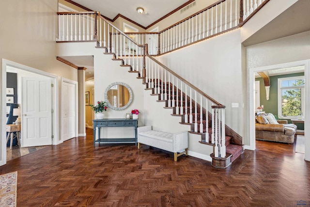 entrance foyer with a high ceiling, stairs, baseboards, visible vents, and ornamental molding