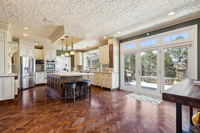 kitchen with french doors, ornamental molding, a kitchen island, and stainless steel appliances