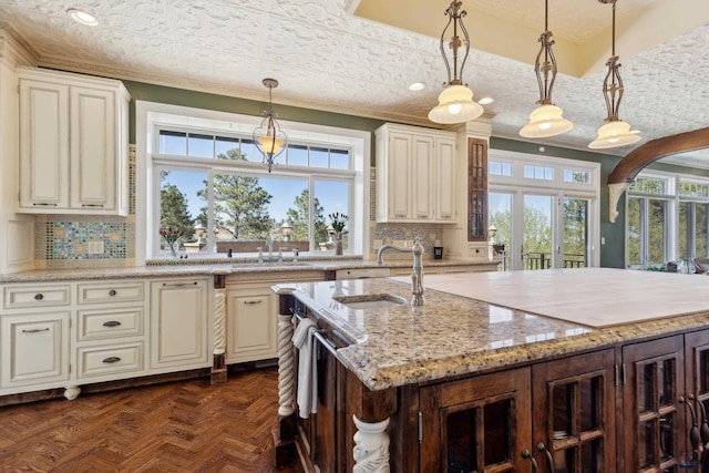 kitchen featuring backsplash, ornamental molding, a sink, and a wealth of natural light