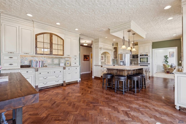 kitchen with crown molding, a breakfast bar area, stainless steel appliances, decorative backsplash, and a kitchen island