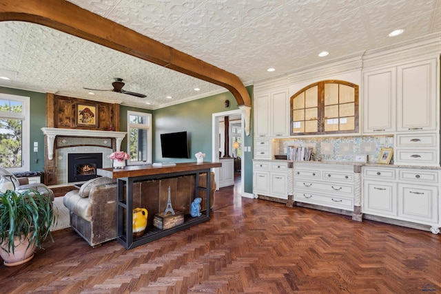 living room with a fireplace, a ceiling fan, baseboards, recessed lighting, and ornamental molding