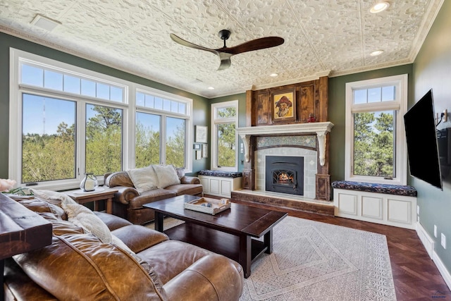 living room featuring ceiling fan, a large fireplace, baseboards, ornamental molding, and recessed lighting