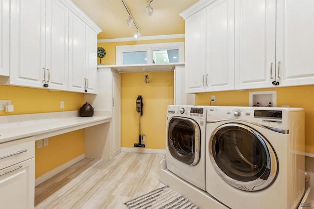 clothes washing area featuring baseboards, cabinet space, washing machine and dryer, and light wood-type flooring