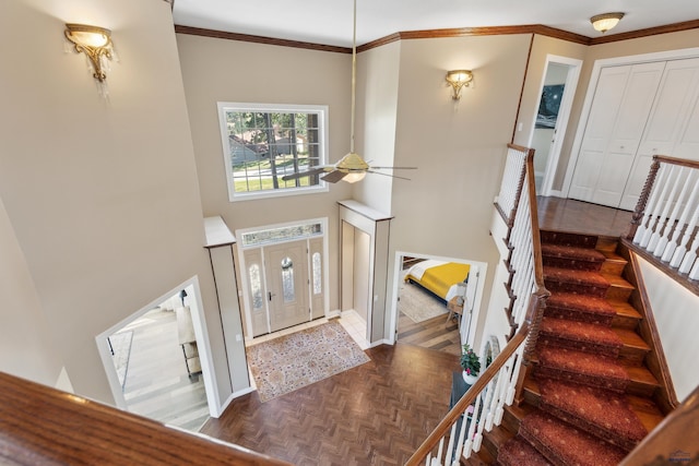 entrance foyer with ceiling fan, crown molding, baseboards, a high ceiling, and stairs
