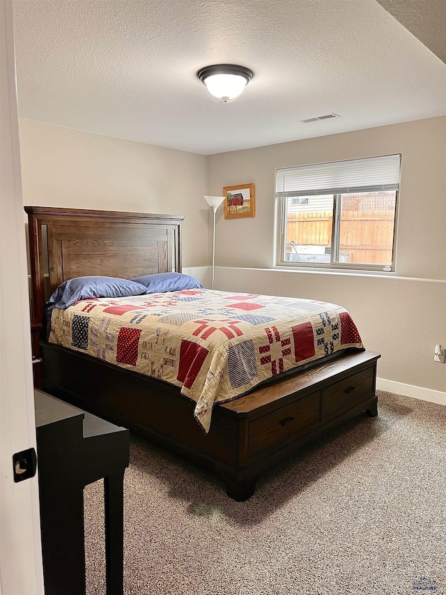 bedroom with baseboards, carpet flooring, a textured ceiling, and visible vents