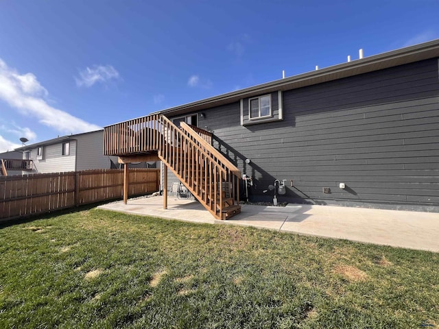 back of property with fence, a deck, a patio, a lawn, and stairway