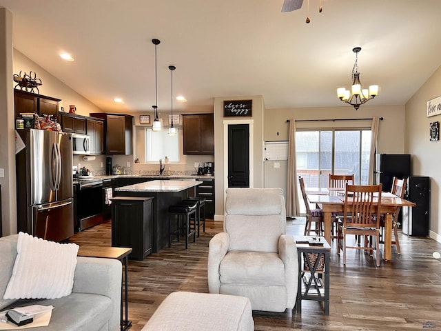 living area with an inviting chandelier, baseboards, dark wood-type flooring, and lofted ceiling