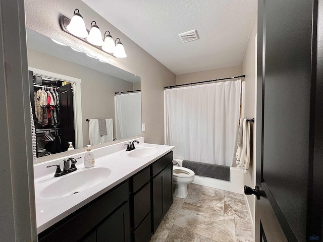 bathroom featuring double vanity, toilet, visible vents, and a sink