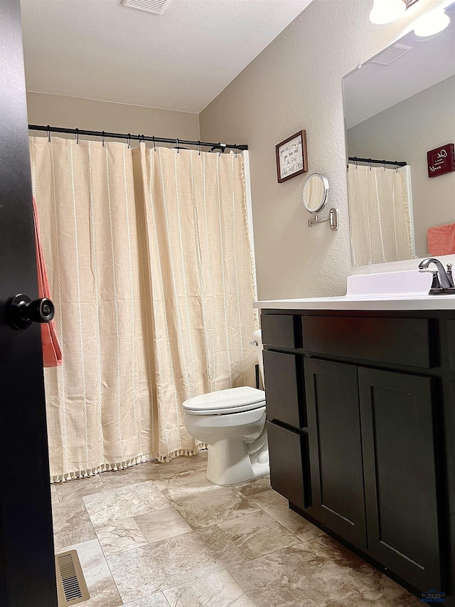 full bathroom with vanity, a textured wall, toilet, and visible vents