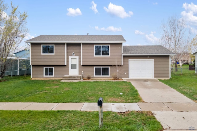raised ranch with a garage, fence, a front yard, and concrete driveway