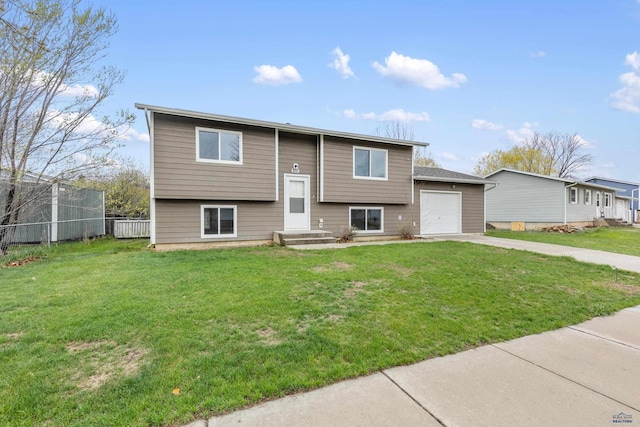 bi-level home with fence, driveway, a front lawn, and a garage