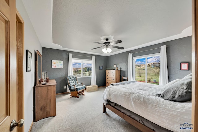 carpeted bedroom with a ceiling fan, a textured wall, and a textured ceiling