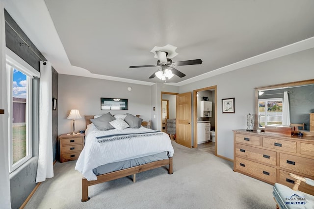 bedroom featuring light colored carpet, baseboards, ceiling fan, and ensuite bath