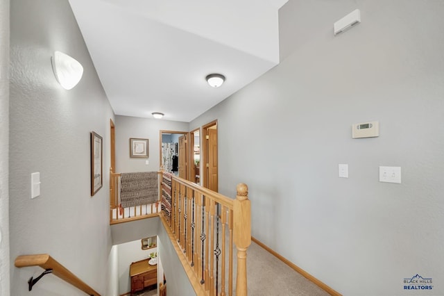 corridor featuring baseboards, carpet flooring, and an upstairs landing