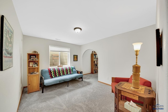 sitting room featuring baseboards, arched walkways, and carpet flooring