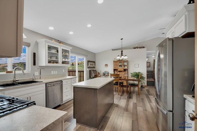 kitchen with a sink, light countertops, lofted ceiling, glass insert cabinets, and stainless steel appliances