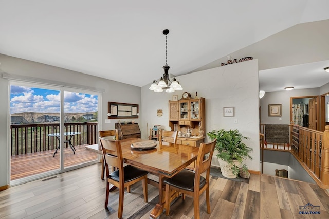 dining area with an inviting chandelier, wood finished floors, and lofted ceiling