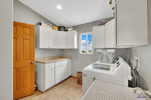 laundry area with light tile patterned floors, separate washer and dryer, and cabinet space